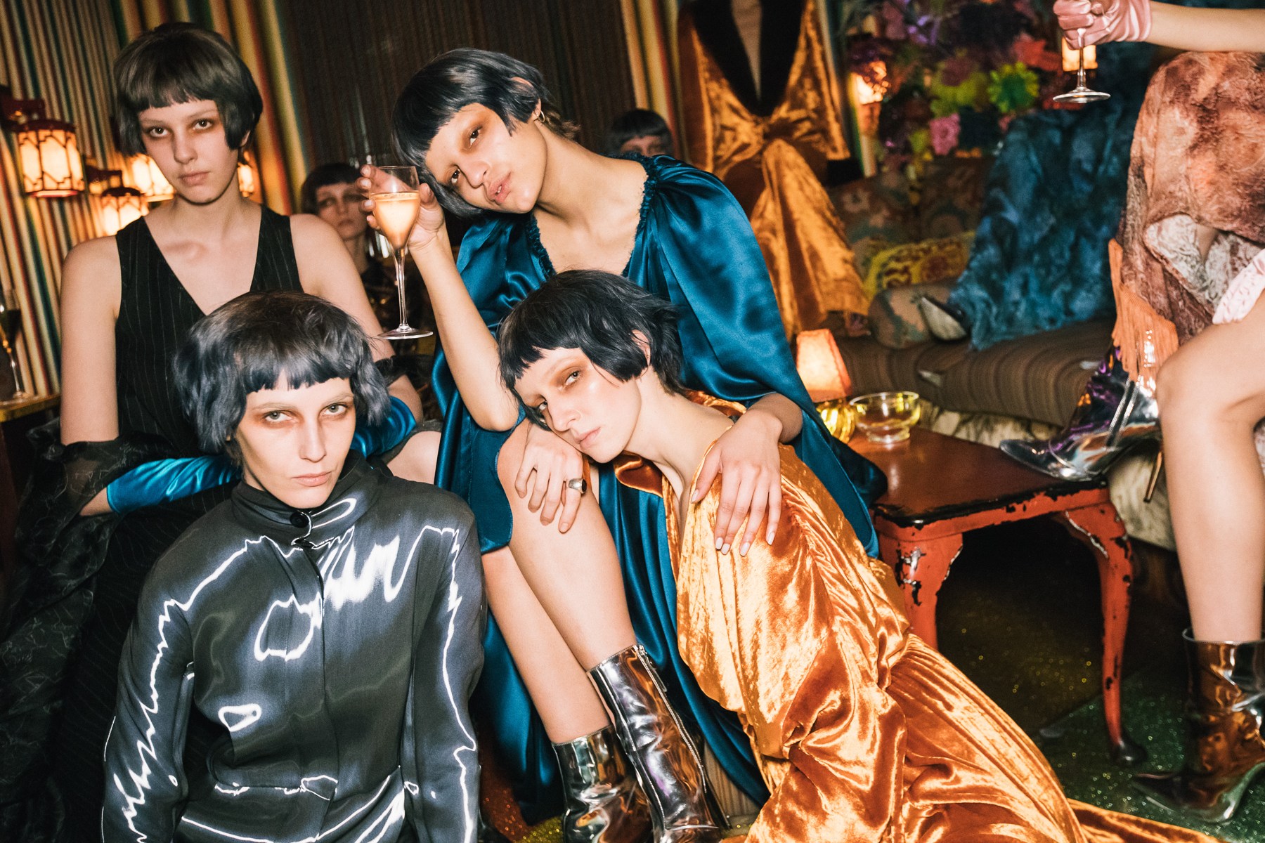 Models wearing Tsarina velvet and metallic pieces gathered on patterned sofas at Loulou’s